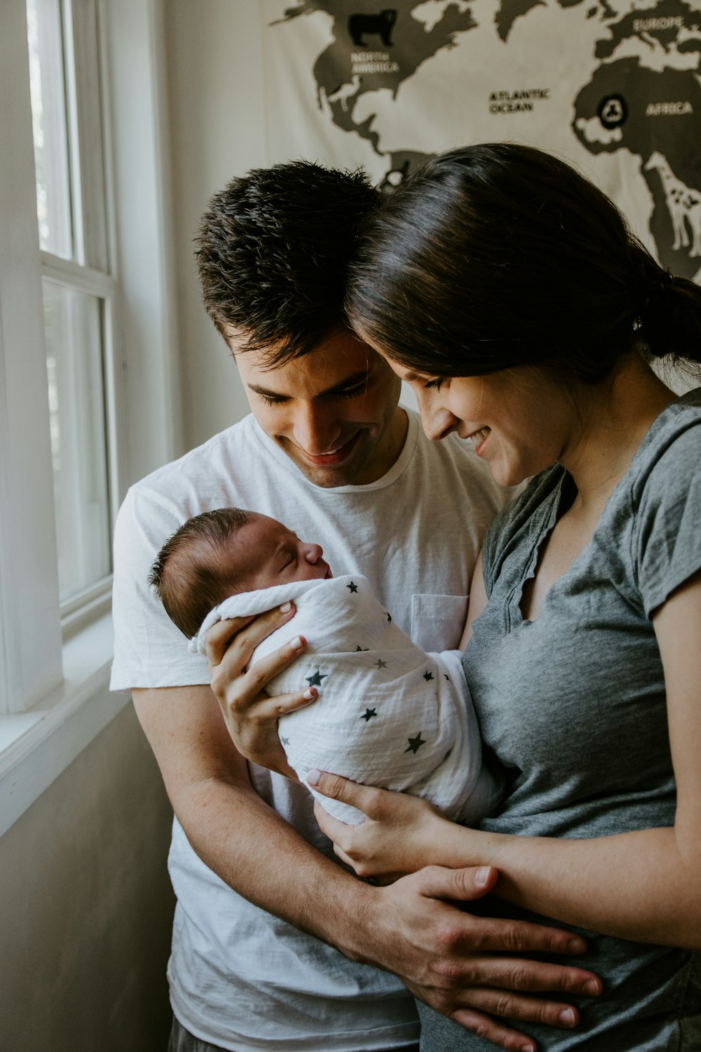 Casal segurando o filho recém-nascido em casa