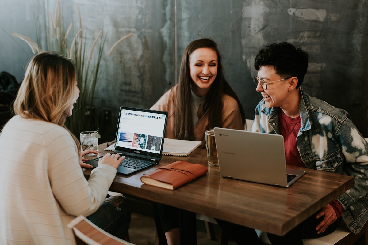 Três mulheres sorrindo durante uma reunião de trabalho